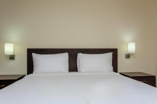 a large white bed with two pillows and two lights at NH Coatzacoalcos in Coatzacoalcos