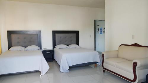 una habitación de hotel con 2 camas y una silla en Hotel Insurgentes Express, en Tepic