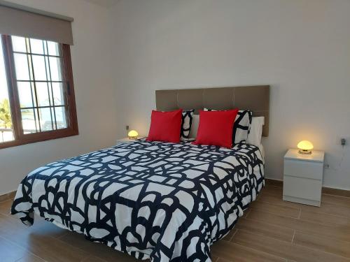 Un dormitorio con una cama en blanco y negro con almohadas rojas en Vv Casa Mercedes puesta de sol, en Vallehermoso