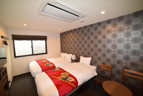 a hotel room with two beds and a window at Laon Inn Gion Nawate in Kyoto