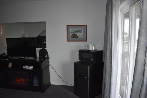 a living room with a television and a fireplace at Lighthouse Cove Inn in Bandon
