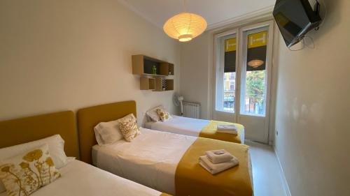 a room with two beds and a tv and a window at INSIDEHOME Valladolid Centro -Hab con baño privado en el centro y OPCION DE PARKING- in Valladolid