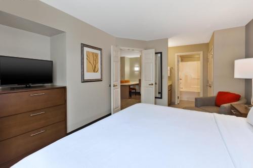 a hotel room with a bed and a television at Staybridge Suites Kalamazoo by IHG in Kalamazoo