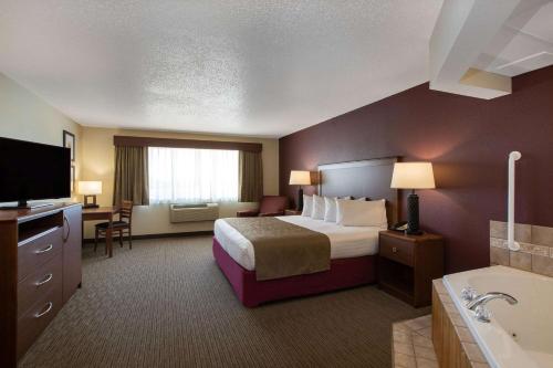 a hotel room with a bed and a bathroom at AmericInn by Wyndham Merrill in Merrill