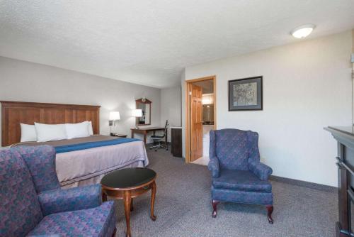 a hotel room with a bed and a table and chairs at Super 8 by Wyndham Port Elgin in Port Elgin