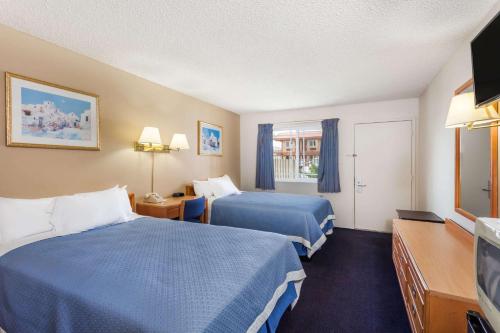 a hotel room with two beds and a flat screen tv at Days Inn by Wyndham Barstow in Barstow