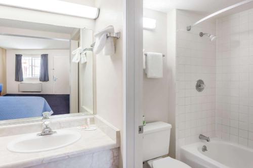 a bathroom with a sink and a toilet and a mirror at Days Inn by Wyndham Barstow in Barstow