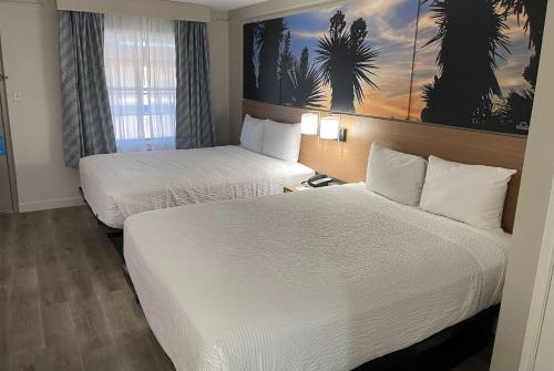 ein Hotelzimmer mit 2 Betten und einem Fenster in der Unterkunft Days Inn by Wyndham Tucson City Center in Tucson