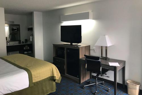 a hotel room with a bed and a desk with a television at Baymont by Wyndham Anderson Clemson in Anderson