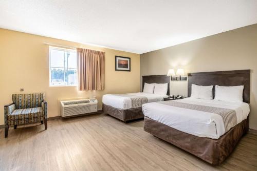 a hotel room with two beds and a chair at Suburban Studios Near Camp Lejeune in Jacksonville