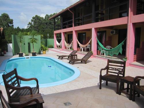 a swimming pool with chairs and a building at Pousada Vento Sul in Florianópolis