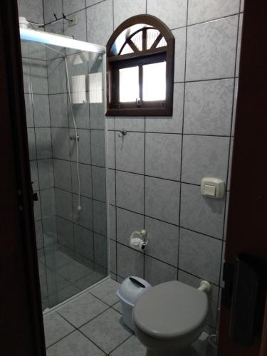 a bathroom with a shower and a toilet and a window at Casa na praia in Itapoa