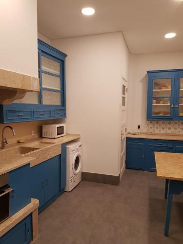 a kitchen with blue cabinets and a washing machine at Rainbow Guest House in Lisbon