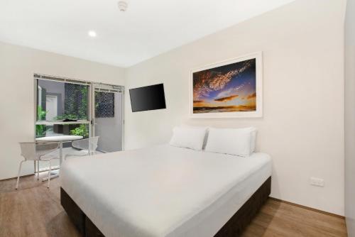 a white bedroom with a large bed and a desk at Bondi Beach Studios Suite in Sydney