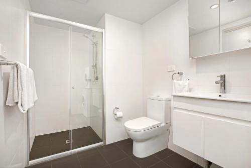 a white bathroom with a toilet and a shower at Bondi Beach Studios Suite in Sydney