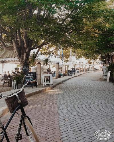 a bike parked on a cobblestone street with trees at Scallywags Beach Club in Gili Air