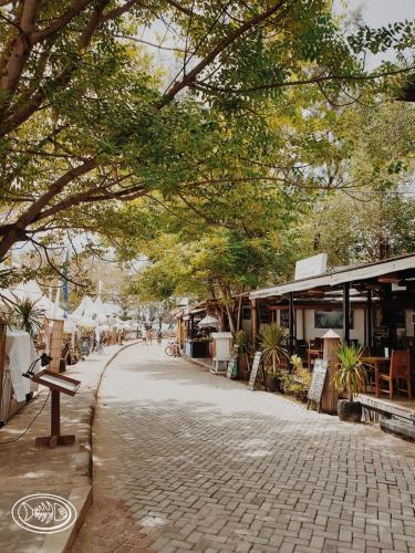 a cobblestone street with trees and shops on it at Scallywags Beach Club in Gili Air