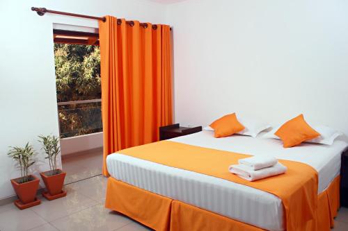 a bedroom with a bed with orange curtains and a window at Hotel Tierra Linda in San Ignacio de Velasco