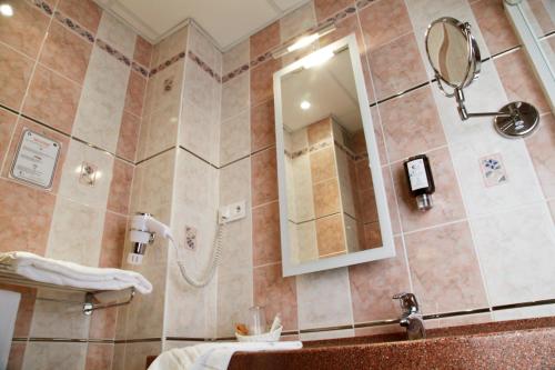 a bathroom with a shower with a sink and a mirror at Hotel Bristol in Châlons-en-Champagne