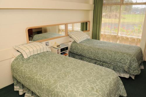 two beds in a room with a mirror and a window at Peninsula Motor Inn in Tyabb