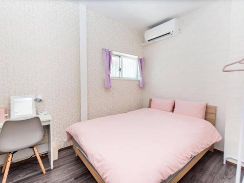 a bedroom with a bed and a desk and a window at El Sol Town Okinawa in Chatan