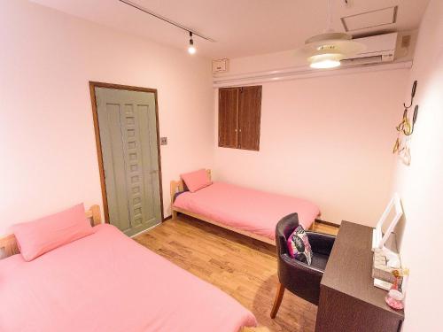 a room with two beds and a desk and a chair at El Sol Town Okinawa in Chatan
