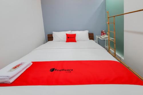 a bed with a red blanket on top of it at RedDoorz Plus @ Batutulis Bogor in Bogor