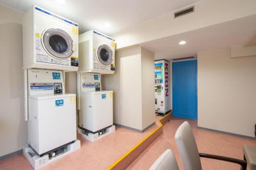 a laundry room with three washers and dryers at Tabist Hotel Ginga Kisarazu in Kisarazu