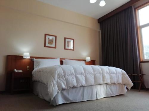 1 dormitorio con 1 cama grande con sábanas blancas en Gran Hotel Isabel Riquelme, en Chillán