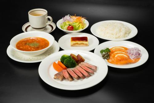 a table with plates of food and a cup of coffee at Tabist Hotel Ginga Kisarazu in Kisarazu