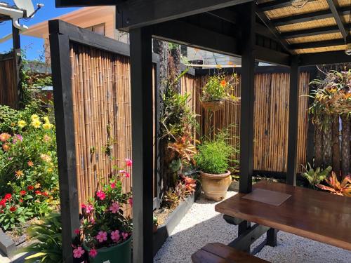 a wooden pergola with a bench and flowers at Opononi Lighthouse Motel in Opononi