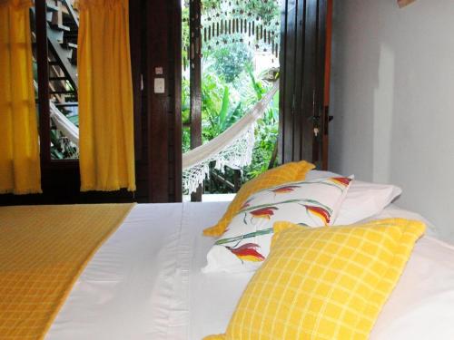 a bed with yellow and white pillows and a window at Pousada Riacho Dos Cambucas in Abraão