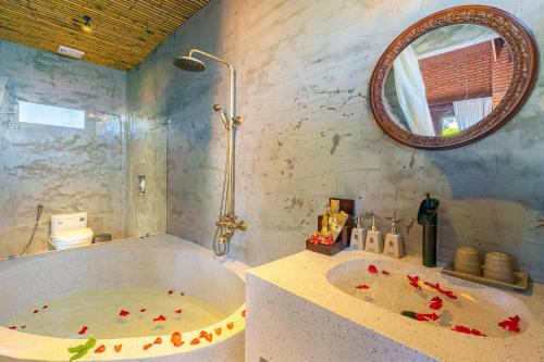 a bathroom with a large tub and a mirror at Angel Garden Villa in Hoi An