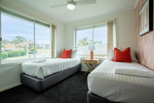 two beds in a room with two windows at Top Of The Quays in Merimbula