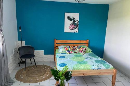- une chambre avec un mur bleu, un lit et une chaise dans l'établissement La Fabuleuse Escapade Robertine, à Le Robert
