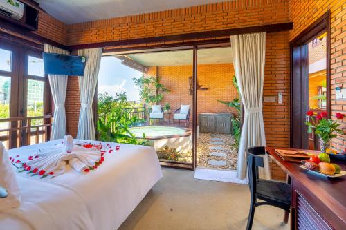 a bedroom with a bed and a balcony with a pool at Angel Garden Villa in Hoi An