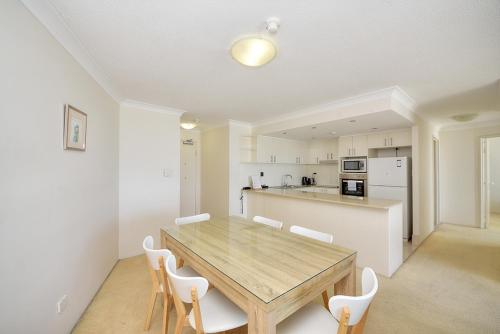 a kitchen with a wooden table and white chairs at 19th Avenue on the Beach in Gold Coast