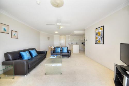 a living room with two leather couches and a television at 19th Avenue on the Beach in Gold Coast