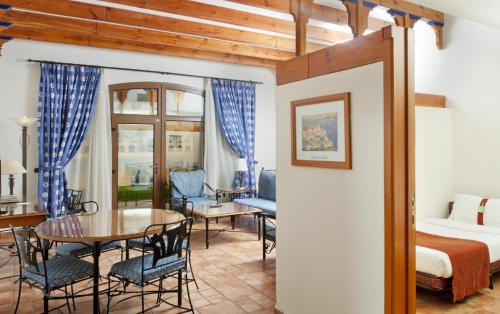 a room with a bed and a table and chairs at Mena Holiday Beach Resort Half Moon in Half Moon Bay