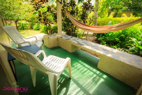 two chairs and a hammock on a porch at Seetanu Bungalows in Srithanu