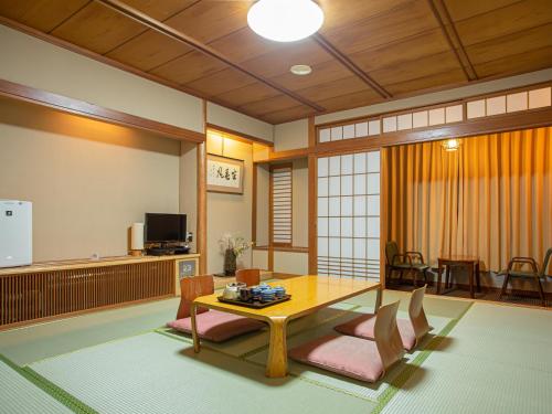 a living room with a table and chairs and a television at Kaneyoshi Ryokan in Osaka