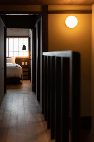 a hallway to a bedroom with a bed and a light at 民家ホテル「金ノ三寸」(かねのさんずん） in Takaoka