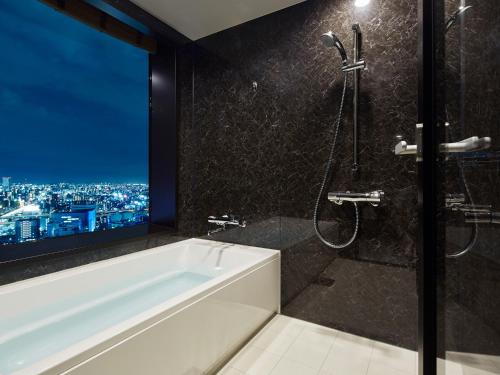 a bathroom with a tub and a shower with a window at Mitsui Garden Hotel Nagoya Premier in Nagoya