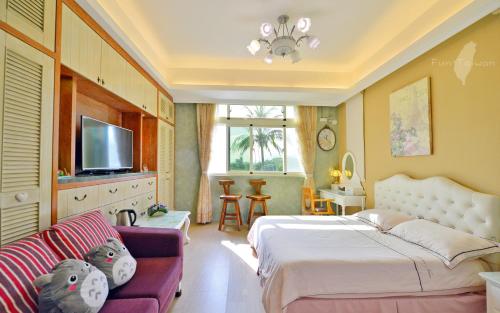 a bedroom with a bed and a couch and a tv at 花蓮 達芙妮花園民宿 in Jian