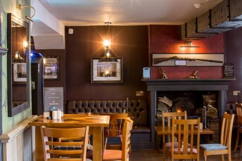 een eetkamer met een tafel en stoelen en een open haard bij The Howard Arms in Brampton