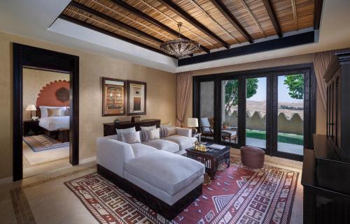 a living room with a white couch and a bedroom at Anantara Qasr al Sarab Desert Resort in Jurayrah