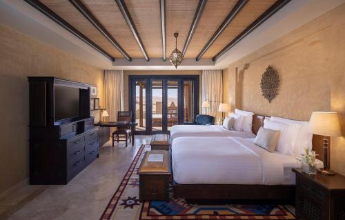 a hotel room with a bed and a television at Anantara Qasr al Sarab Desert Resort in Jurayrah