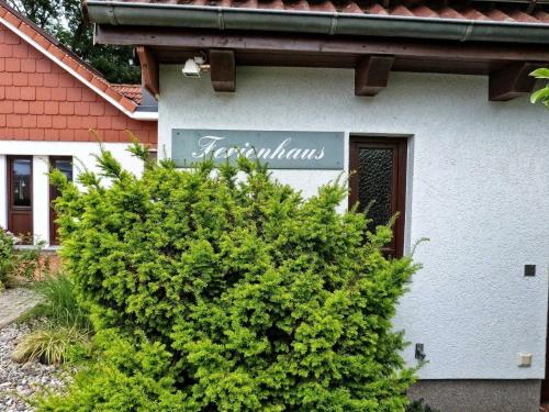 a sign on the side of a house with a bush at Familie Heisch - Gemütliches Ferienhaus mit Terrasse und Strandkorb in Schafflund