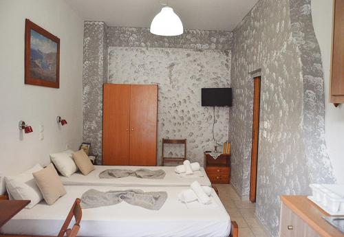 a bedroom with two beds and a tv on a wall at ''Studios Anna'' in Lentas