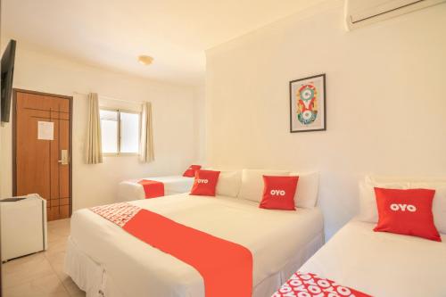 - 2 lits dans une chambre rouge et blanche dans l'établissement OYO Hotel Diamante Negro - Salvador, à Salvador